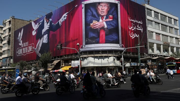 Cars pass a large billboard of Donald Trump on a building in Tehran