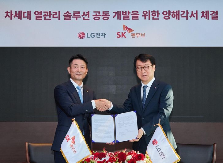 SK Enmove CEO Kim Wone-kee, left, shakes hands with LG Electronics Eco Solution Division President Lee Jae-sung after signing a memorandum of understanding on the joint development of refrigerants, lubricants and immersion cooling technologies at the former's office in Jongno District, Seoul, Monday. Courtesy of SK Enmove