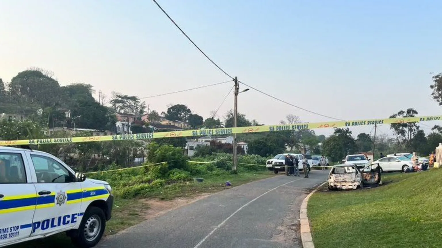 SAPS A yellow police tape with the words SA Police Service with several vehicles in the background