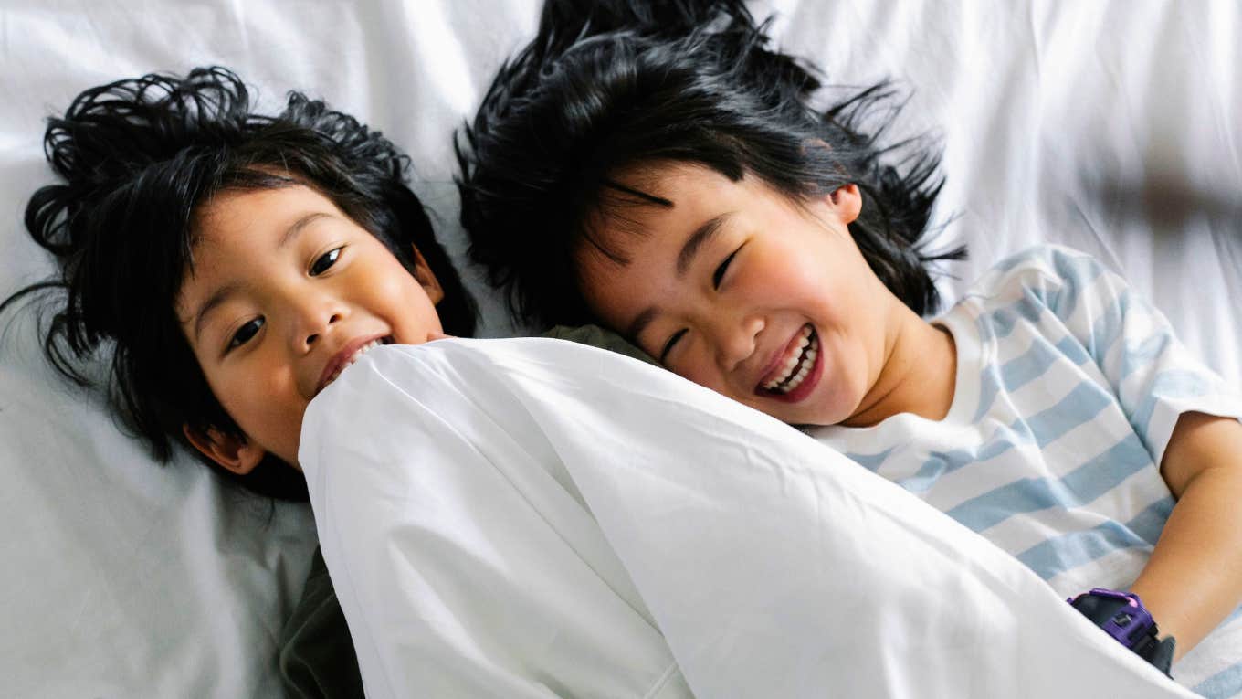 siblings sharing a bed laughing playing together