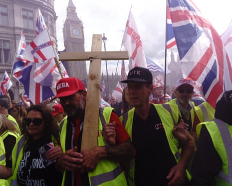 Rally crowd holds a wooden cross and Union Jack flags near Big Ben in London